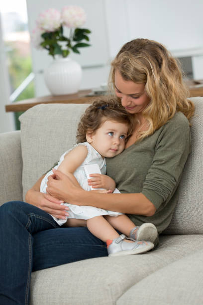 istock mother hugging little girl on sofa 874659450