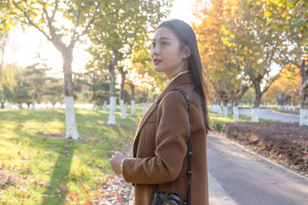istock Young woman carrying camera walking at park trail 874663620