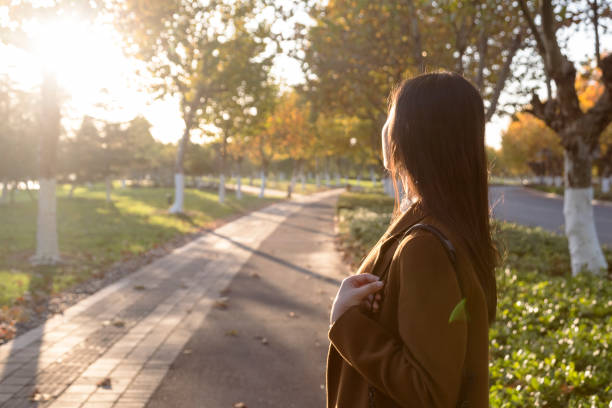 istock Young woman carrying camera walking at park trail 874663626