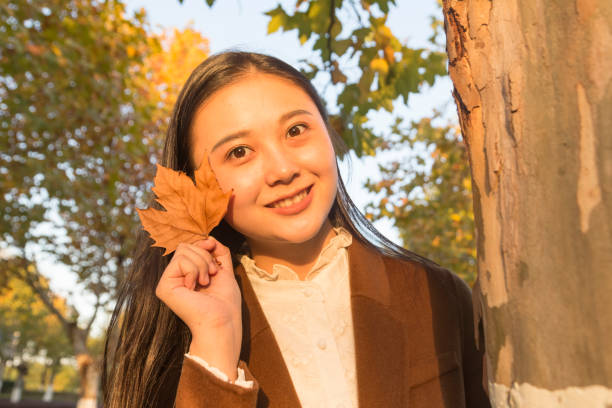 Sixteen year old girl wearing brown by an old oak tree.