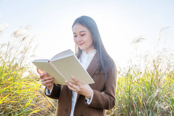 istock attractive woman reading books amidst reed plants 874672572