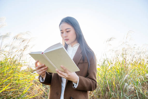 istock attractive woman reading books amidst reed plants 874672778