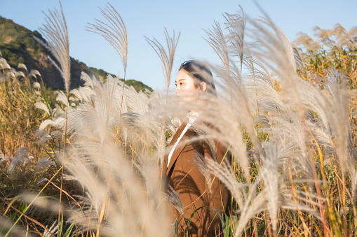 portrait of a young beautiful woman standing among reeds in autumn,china.