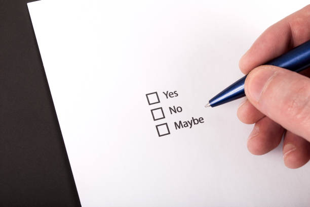 istock Check boxes and yes, no, maybe question and hand with pen on white paper 874676798