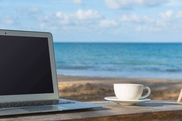 istock Laptop and a cup of coffee sea view 874677060