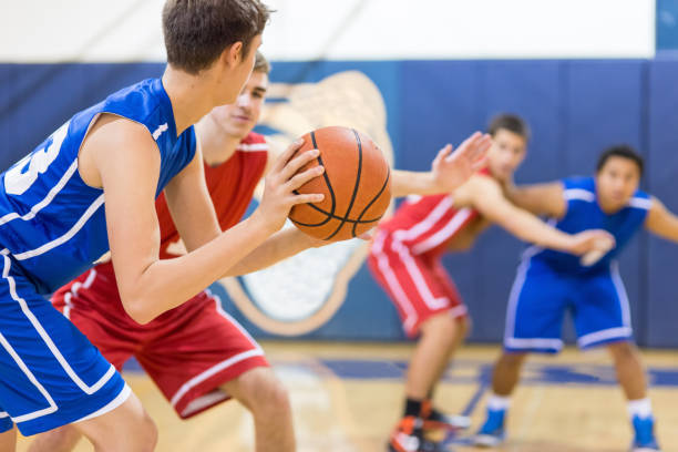 The final minutes... A high school basketball player holds the ball carefully outside the key as he's guarded. He's trying to decide who to pass to... offense sporting position photos stock pictures, royalty-free photos & images