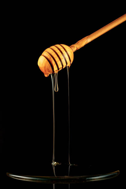 istock Spoon of honey. On a black background. Dripping fresh honey. 874686222