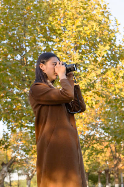 istock woman photographing with camera in park 874690184