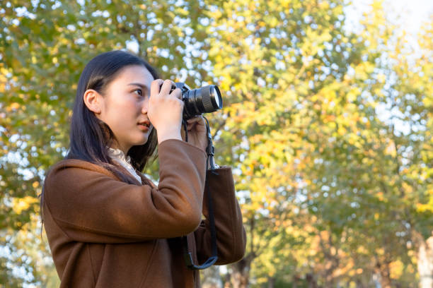 istock woman photographing with camera in park 874690218