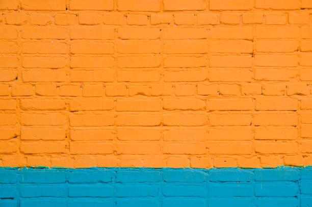 istock brick wall painted wit orange-blue color. saturated color. 874697302