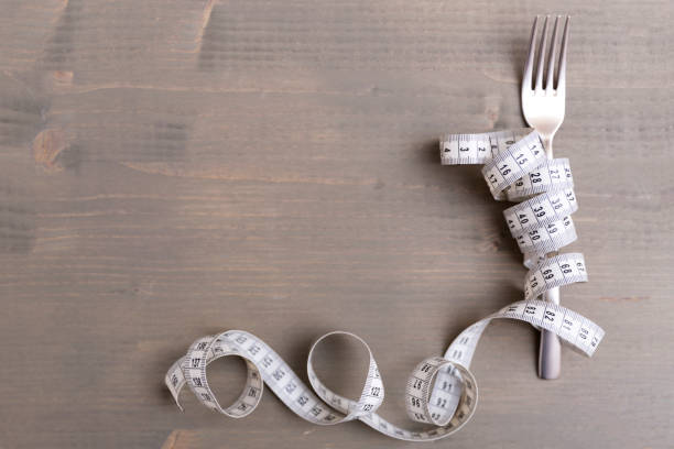 istock Diet concept, fork and measuring tape isolated on wooden background 874706936