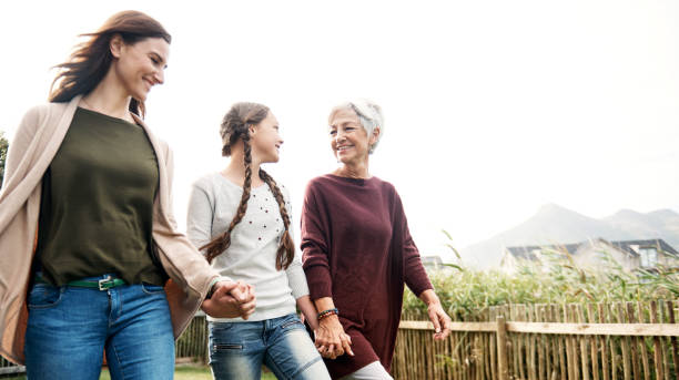 Shot of a happy family of three females walking hand in hand and smiling while walking together in the garden outside