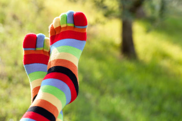 Woman feet with colored socks with fingers in green grass.