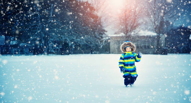 chłopiec w dzianym kapeluszu, rękawiczkach i szaliku na zewnątrz przy opadach śniegu - skiing family winter snow zdjęcia i obrazy z banku zdjęć