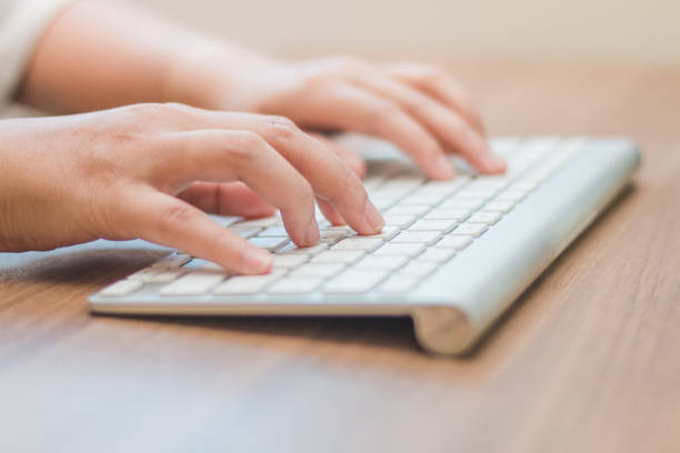 istock Close-up hand typing  white keyboard on wooden table 874716982
