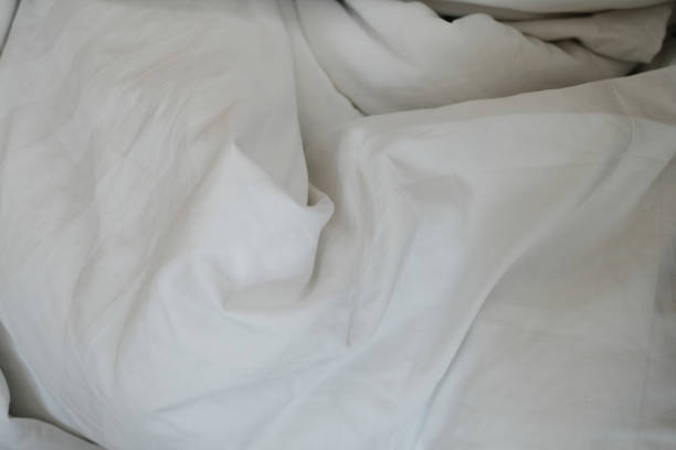 istock White delicate soft background of fabric or bedding sheet in dark room. 874719394