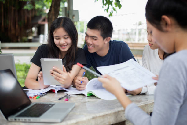 istock Asian Group of students using tablet and notebook sharing with the ideas for working on the campus lawn 874723954
