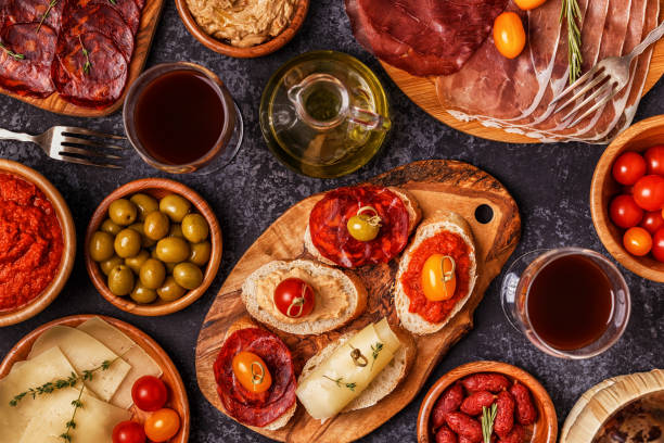 istock Typical spanish tapas concept. Concept include slices jamon, chorizo, sausage, bowls with olives, tomatoes, anchovies,  mashed chickpeas, cheese. 874724192