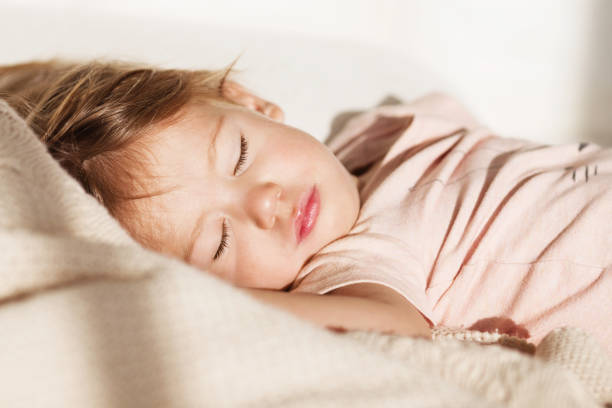 carefree sleep little baby with a soft toy on the bed. close-up portrait of a beautiful sleeping child on knitted blanket. sweet dreams - sleeping child bedtime little girls imagens e fotografias de stock