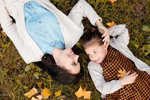 Top view shot of mother and little daughter lying on grassy lawn