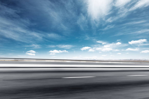 istock empty asphalt road with snow mountains in blue cloud sky 874738704