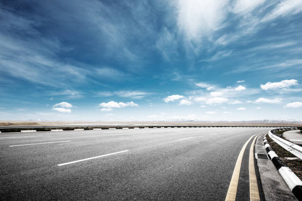 istock empty asphalt road with snow mountains in blue cloud sky 874741274
