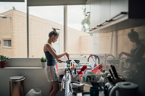 A young woman makes pancakes for breakfast.