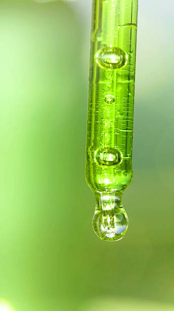 istock Transparent pipette with oil on a green background 874747022