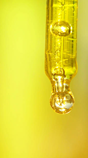 istock Transparent pipette with oil on a gold background 874747146