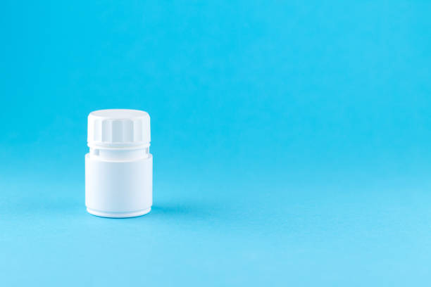 istock Close up white pill bottle on blue background with copy space. Focus on foreground, soft bokeh. Pharmacy drugstore concept 874751762