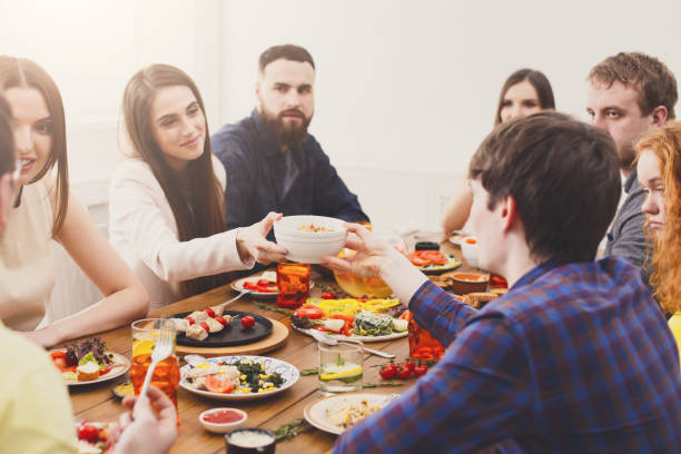 istock Group of young people at festive table dinner party 874754506