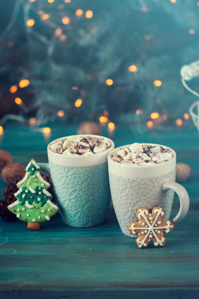 istock Hot chocolate with marshmallows, cinnamon and spices on a blue background with fir and christmas lights 874757572