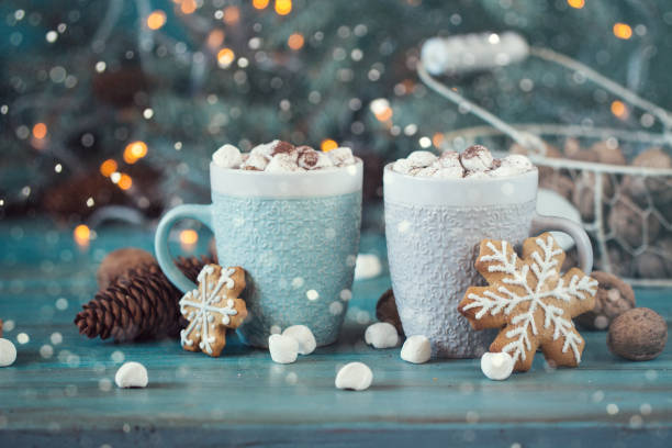 istock Hot chocolate with marshmallows, cinnamon and spices on a blue background with fir and christmas lights 874757630