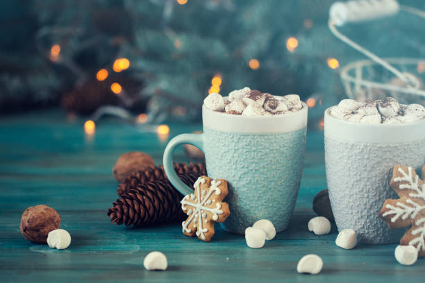 istock Hot chocolate with marshmallows, cinnamon and spices on a blue background with fir and christmas lights 874758106