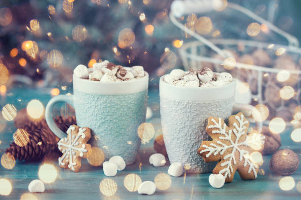 istock Hot chocolate with marshmallows, cinnamon and spices on a blue background with fir and christmas lights 874758146