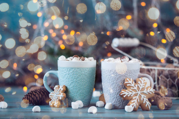istock Hot chocolate with marshmallows, cinnamon and spices on a blue background with fir and christmas lights 874758294