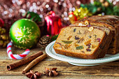 Homemade delicious soft and moist rum fruits cake or Christmas fruits cake with rich dried fruit and nuts slices on wood plate put on wood table with copy for party and celebration. Bakery concept.