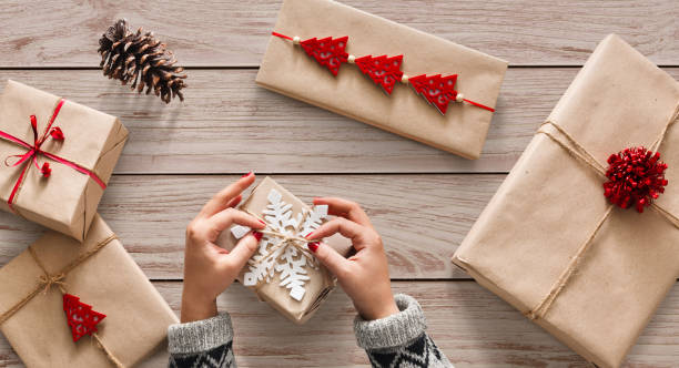 istock Woman's hands wrapping christmas holiday present with craft twin 874765400