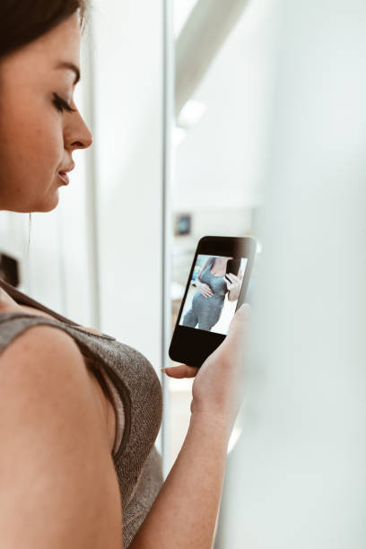 istock pregnant woman take a selfie on the mirror 874780392