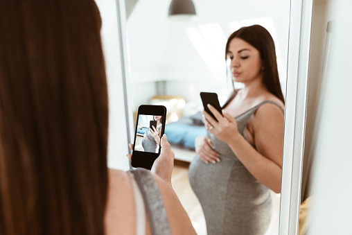 pregnant woman take a selfie on the mirror