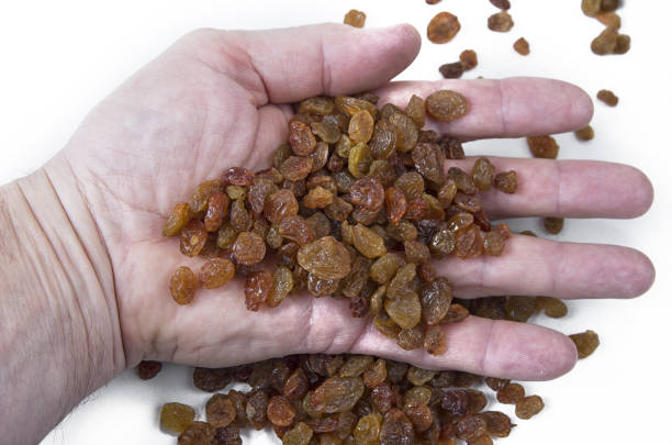 istock Sweet raisins in the hand on white background 874780686