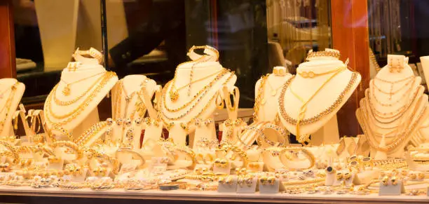 Photo of Jewelry gold necklaces rings bracelets watch wealth,  Jewellery shops on Ponte Vecchio bridge in Florence, Italy, Gold background.