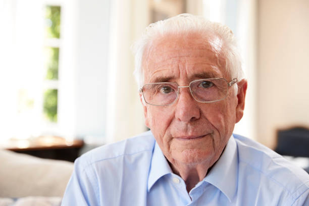 porträt von senior mann sitzt auf dem sofa, die unter depressionen leiden - senior adult depression dementia alzheimers disease stock-fotos und bilder