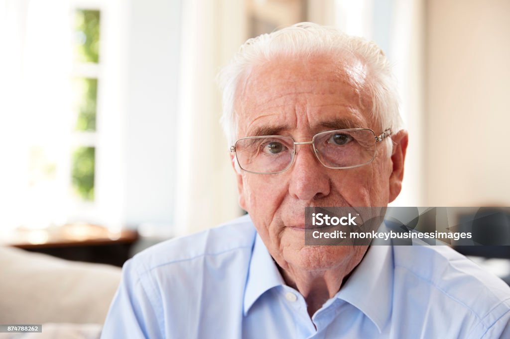 Portrait Of Senior Man Sitting On Sofa Suffering From Depression Senior Men Stock Photo