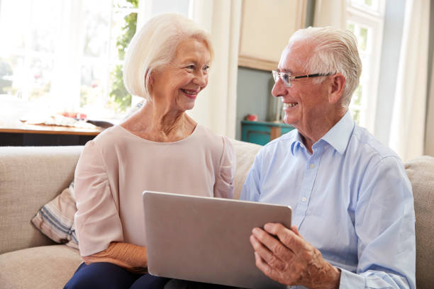 istock Senior Couple Sitting On Sofa Using Laptop At Home Together 874788828