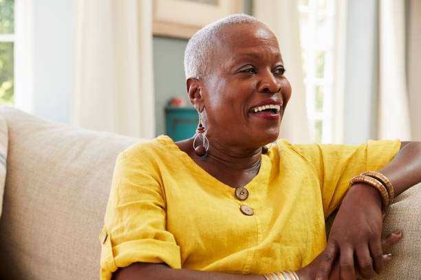 Smiling Senior Woman Sitting On Sofa At Home