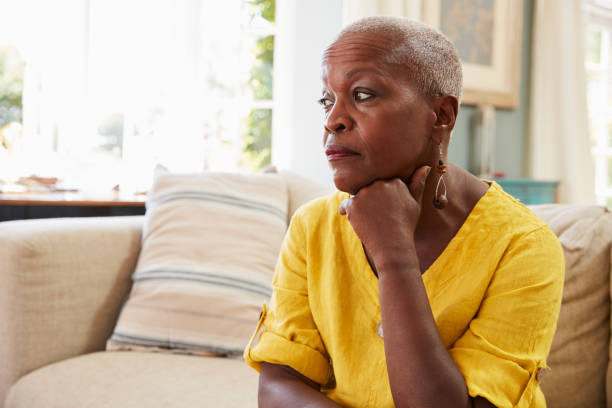 haute femme assise sur le canapé à la maison souffrant de dépression - senior women depression sadness women photos et images de collection