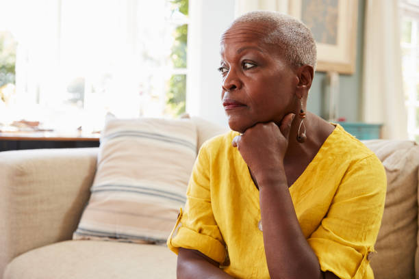 donna anziana seduta sul divano di casa affette da depressione - adult loneliness depression foto e immagini stock
