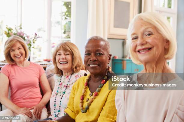 Portrait Of Senior Female Friends Relaxing On Sofa At Home Stock Photo - Download Image Now