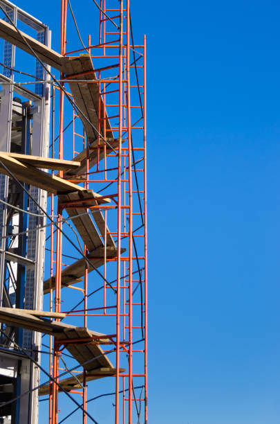 istock scaffolding around the building under construction against a bright blue sky. vertical picture 874804014